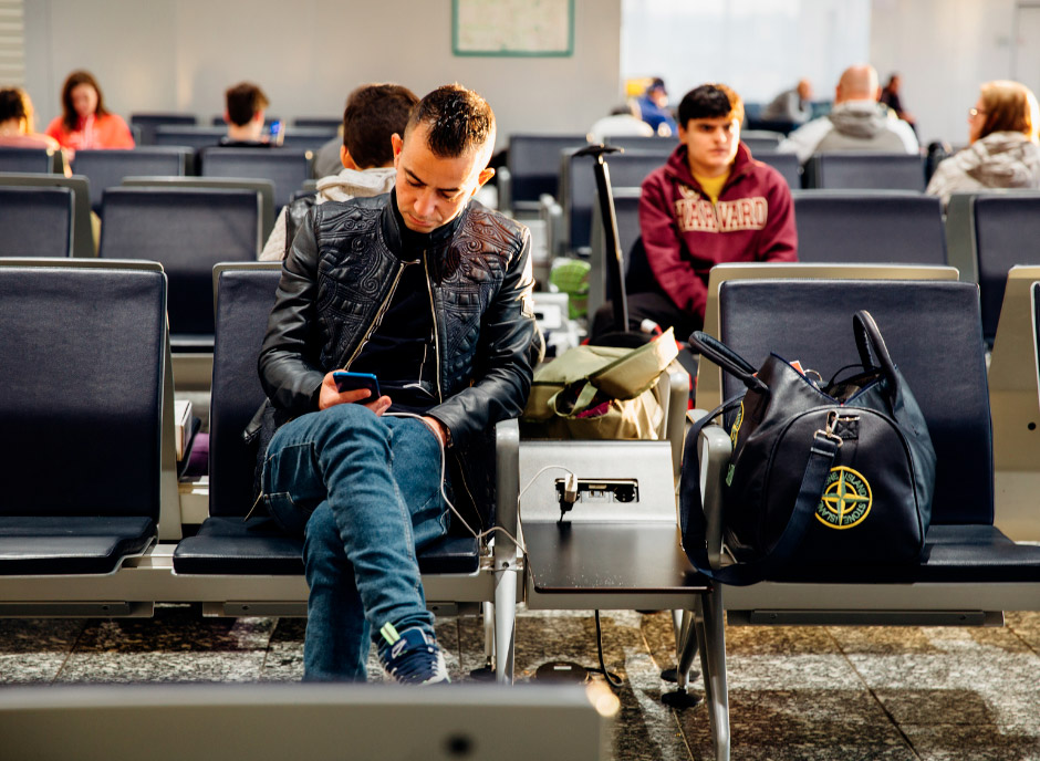 chlap �akaj�ci na letisku hraj�ci sa na mobile